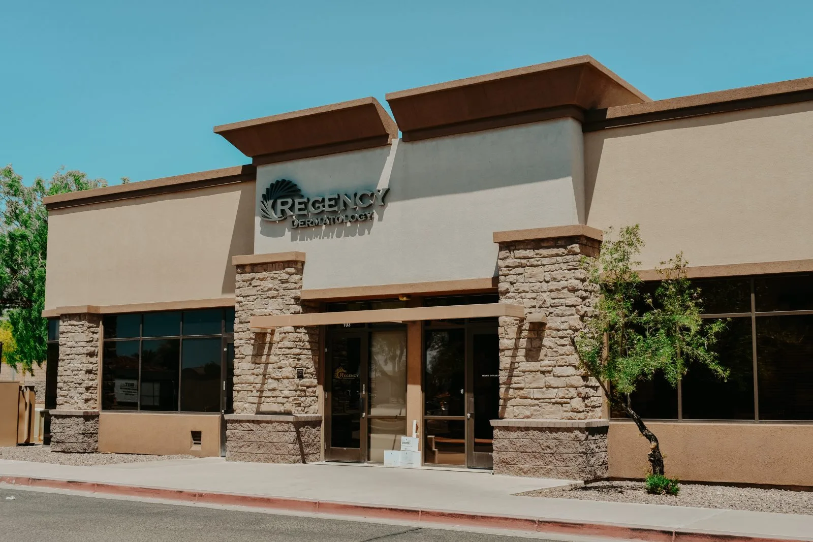 Regency Dermatology exterior storefront with stone and stucco facade under clear blue sky